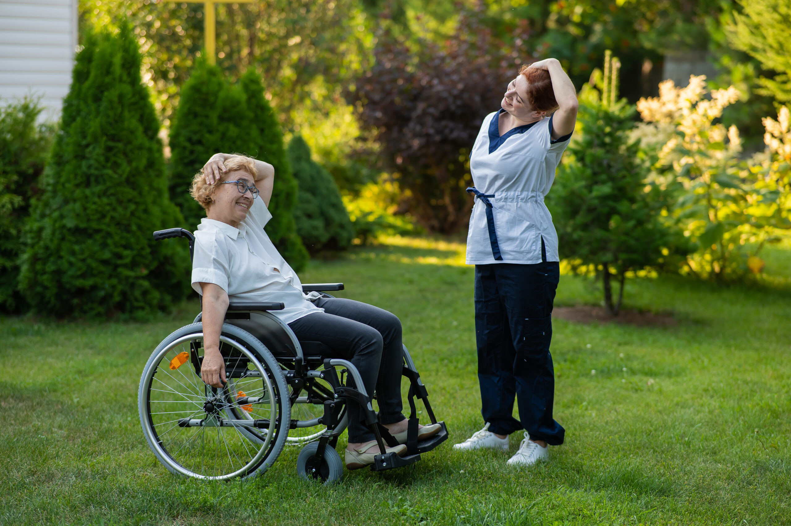 A nurse is exercising with an elderly patient in a wheelchair outdoors. A nurse is exercising with an elderly patient in a wheelchair outdoors.